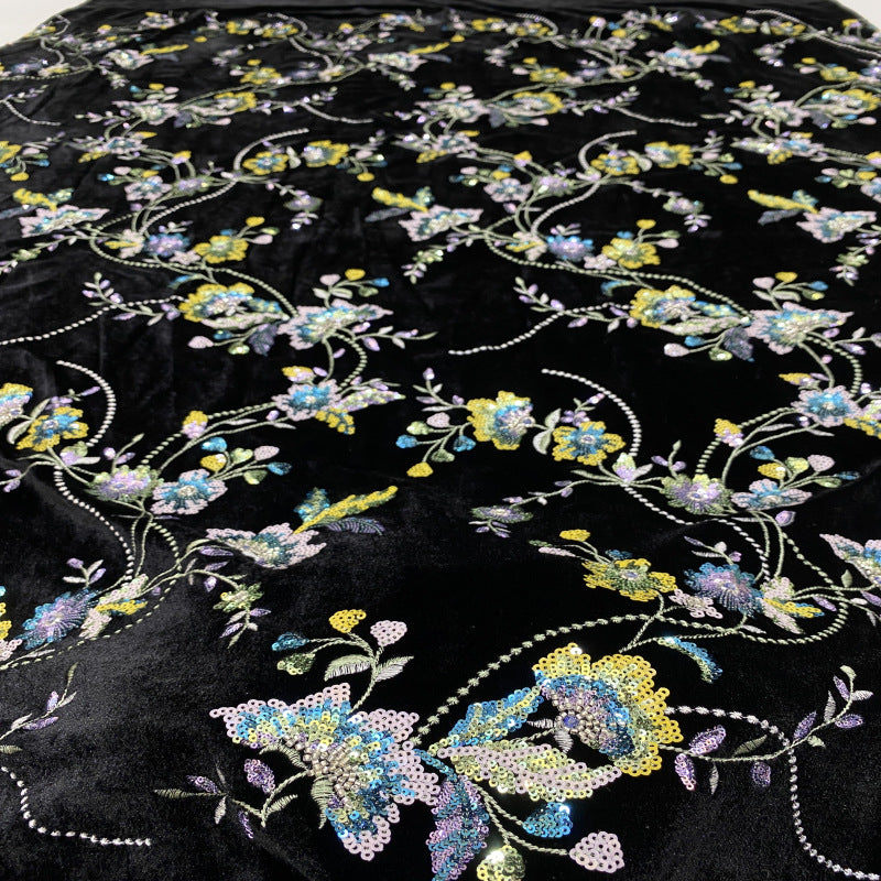 Close-up of sequined blue, cream and yellow floral embroidery on black velvet