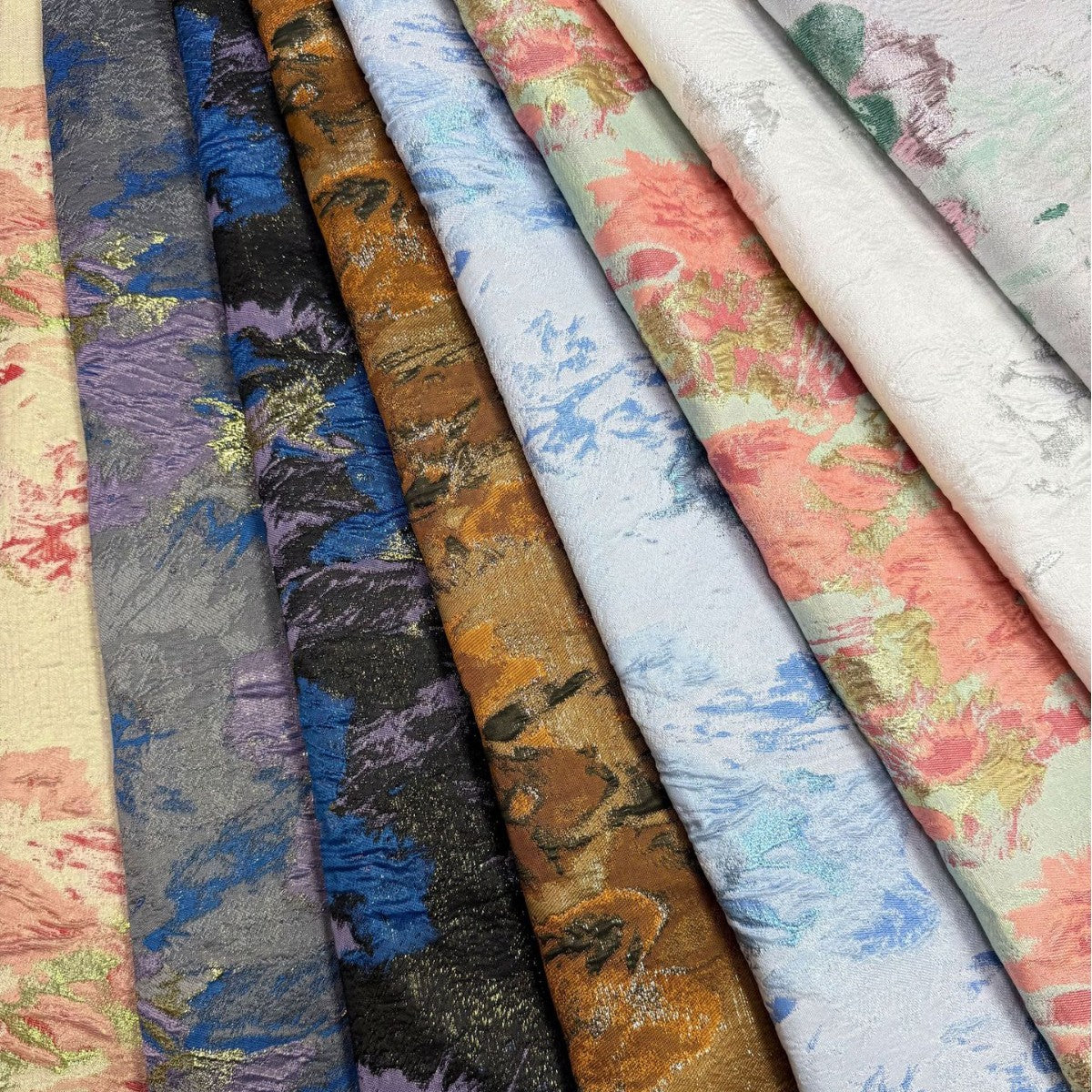 Folded rolls of floral and metallic decorative organza with different color patterns