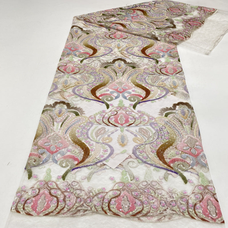 Decorative guipure lace fabric with pink, gold and cream ornate floral patterns laid flat