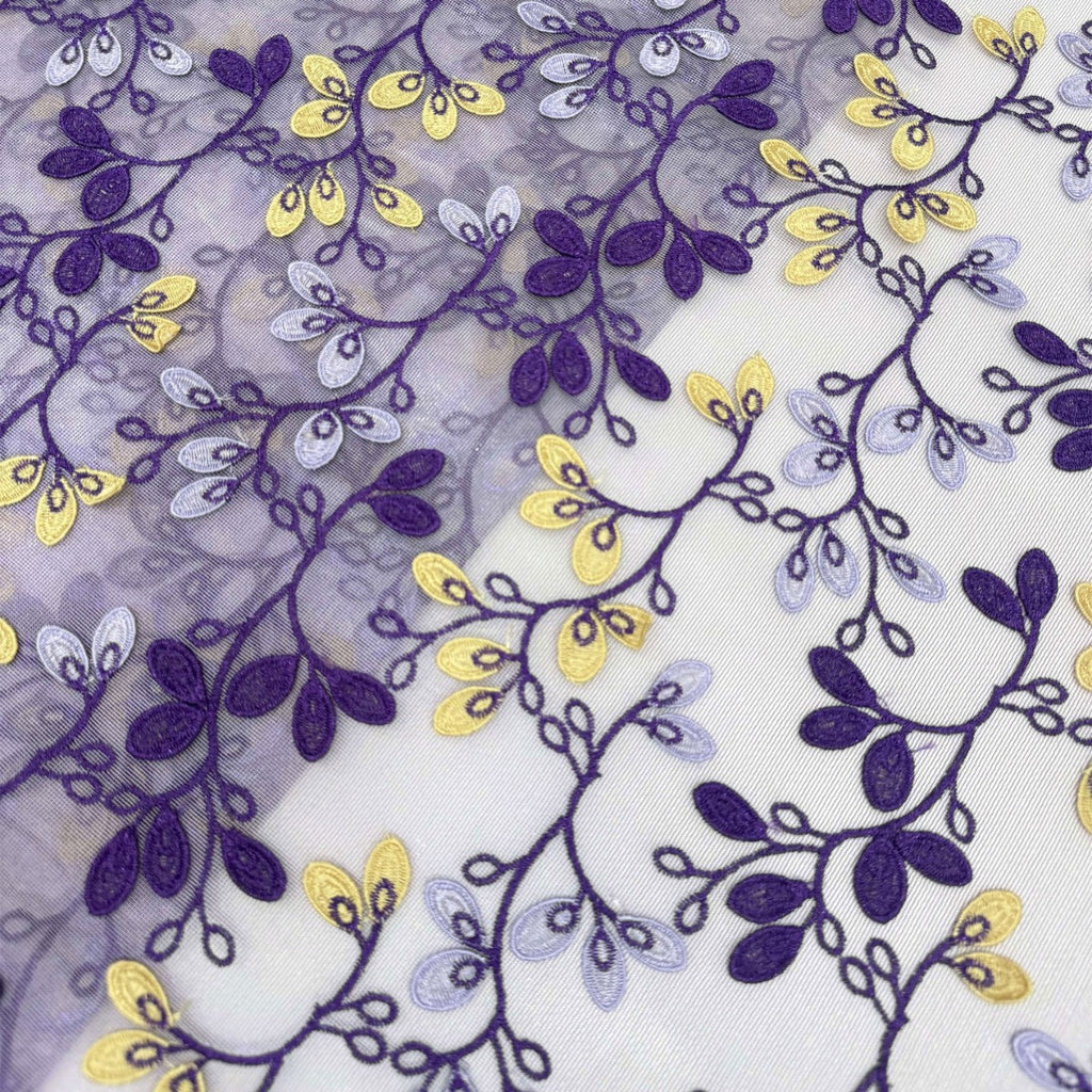 Close-up of purple and yellow embroidered vines and leaves across transparent chiffon