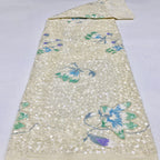 Beige velvet-base sequined fabric laid out with blue-green and lavender floral motifs