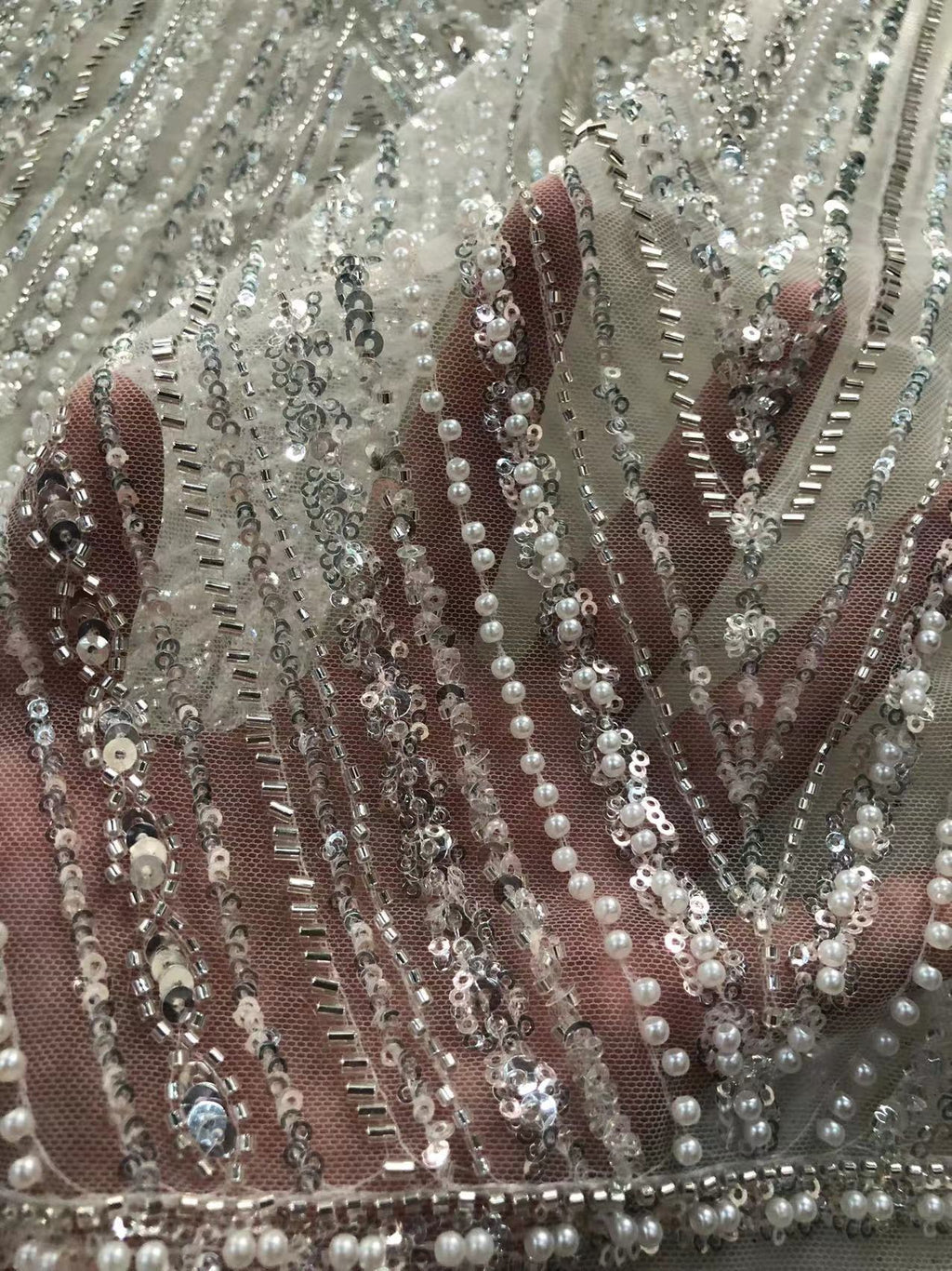 Hand beneath silver-beaded embroidered sheer fabric to show raised texture and transparency