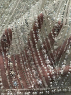 Hand beneath silver-beaded embroidered sheer fabric to show raised texture and transparency