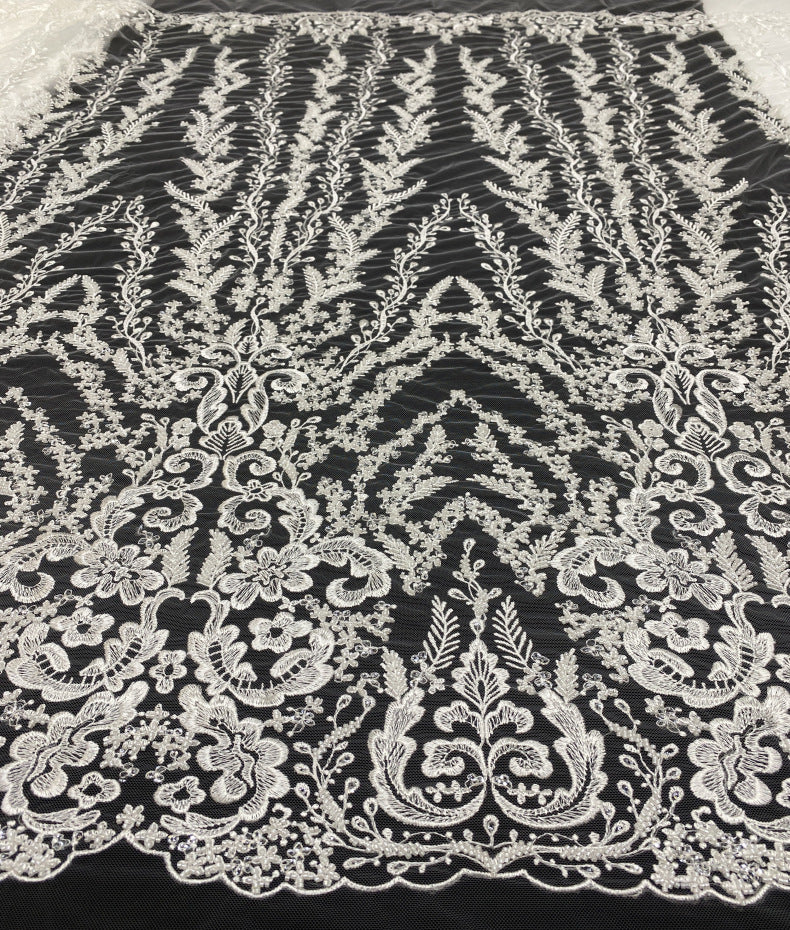 Close-up of ivory-white embroidered scrolling floral motifs on black mesh