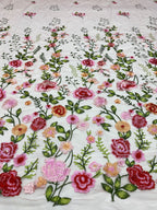 Close-up of multicolored rose and leaf thread embroidery on light sheer fabric