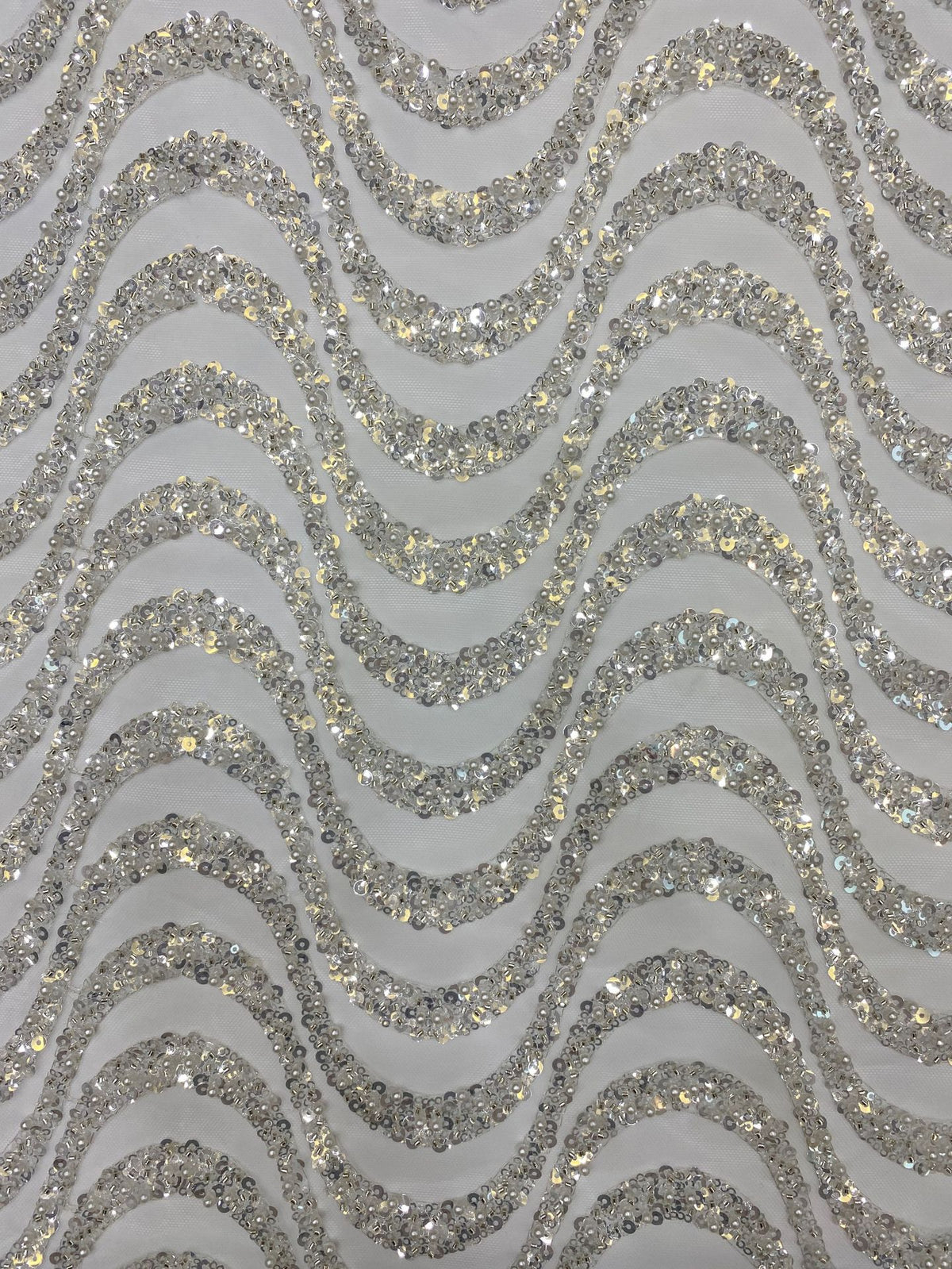 Detailed view of silver sequined wavy embroidery and translucent fabric ground