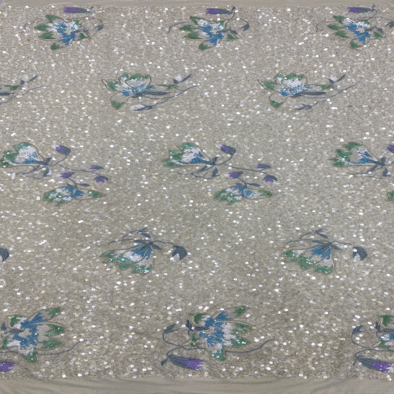 Close-up of blue and teal floral embroidery and scattered sequins on beige velvet base