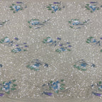 Close-up of blue and teal floral embroidery and scattered sequins on beige velvet base