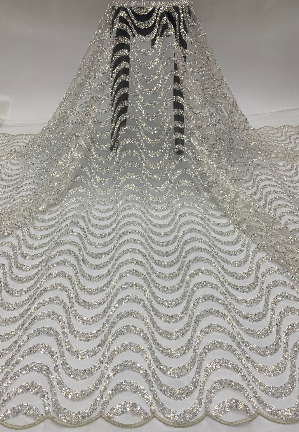 Silver sequin and bead embroidered bridal mesh hanging in a full drape with repeating wave motifs