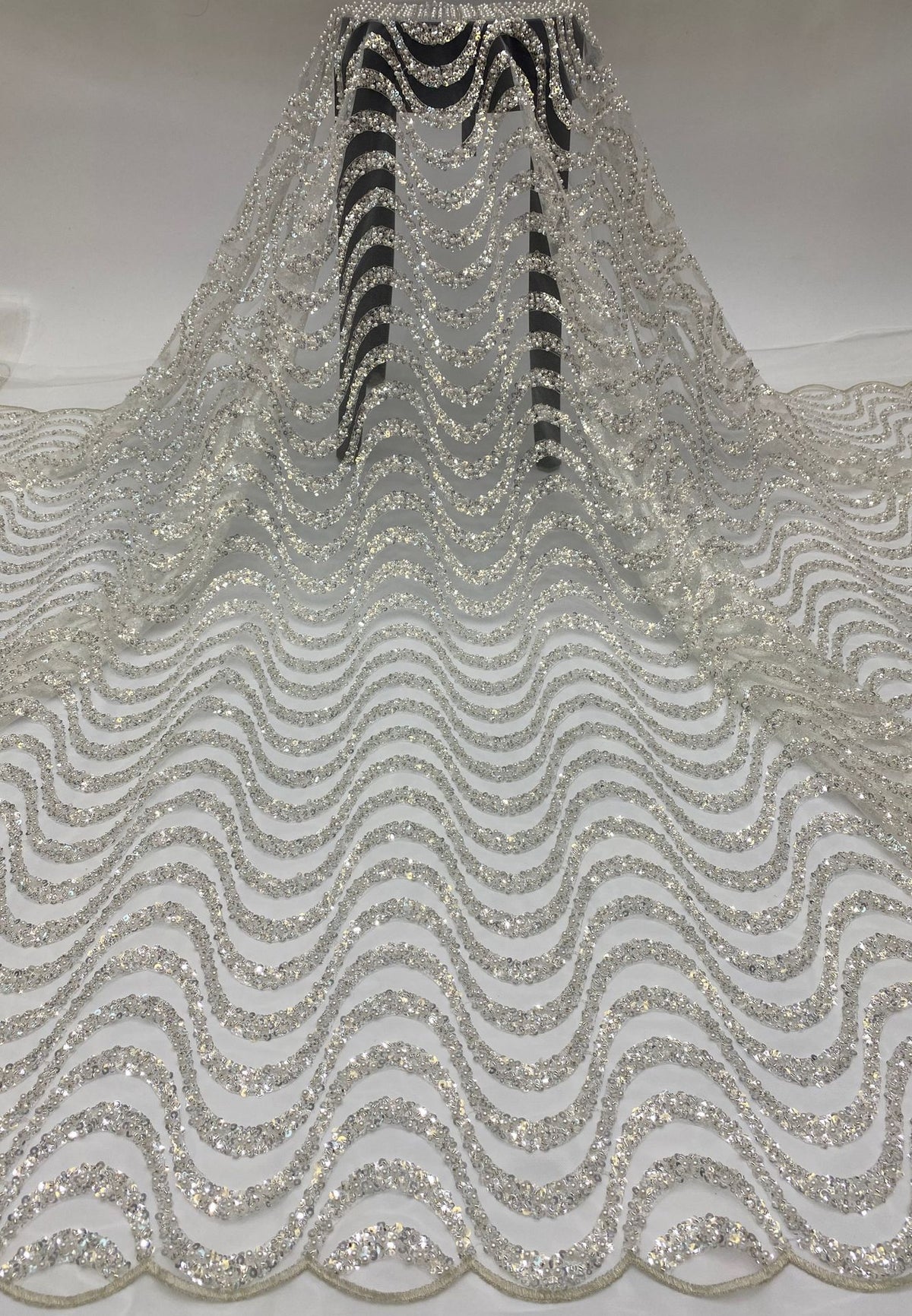 Silver sequin and bead embroidered bridal mesh hanging in a full drape with repeating wave motifs