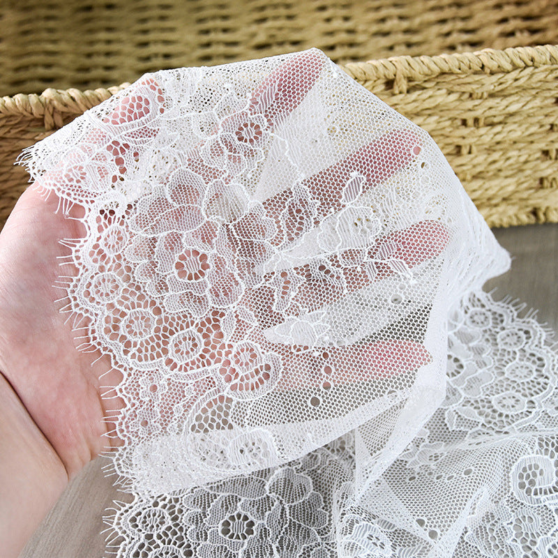 White floral lace trim held in a hand to show sheer openwork and edge detail