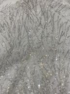 Detailed view of shimmering silver branch embroidery on pale mesh fabric
