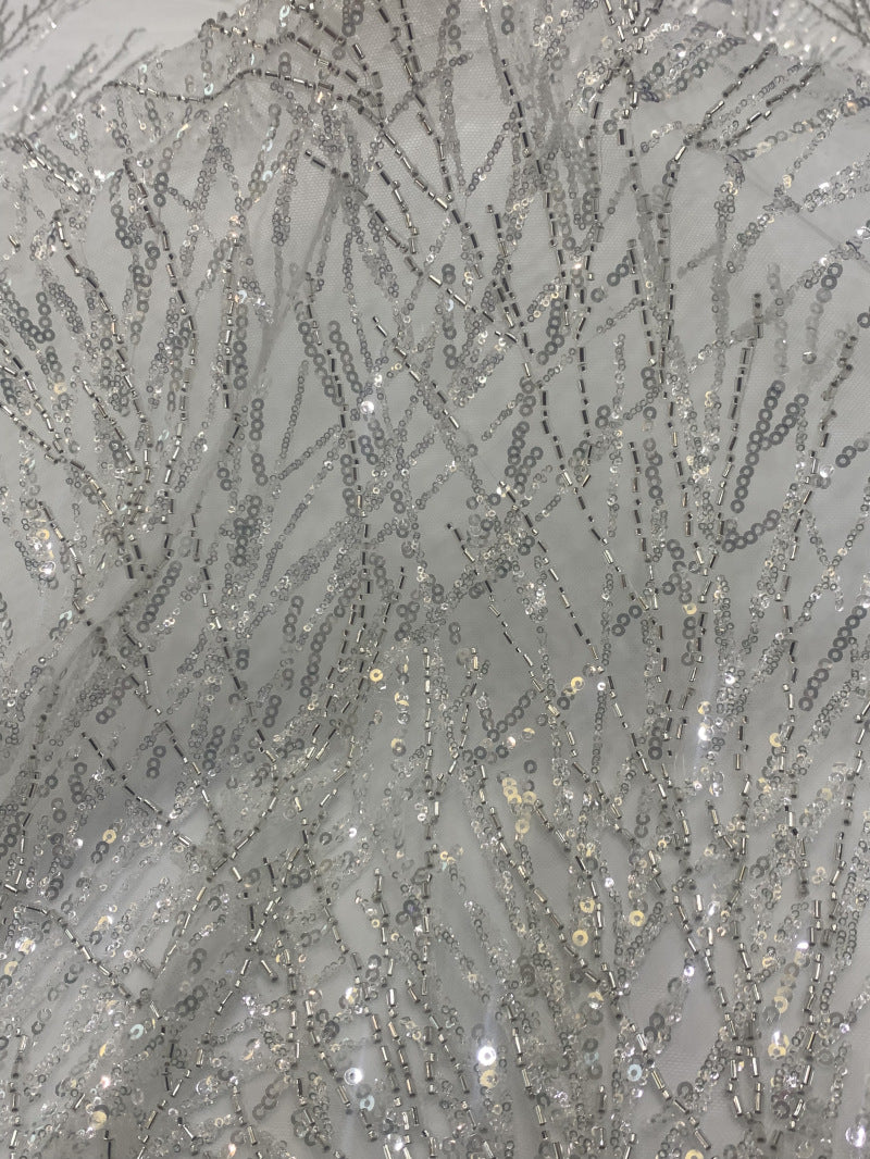 Detailed view of shimmering silver branch embroidery on pale mesh fabric