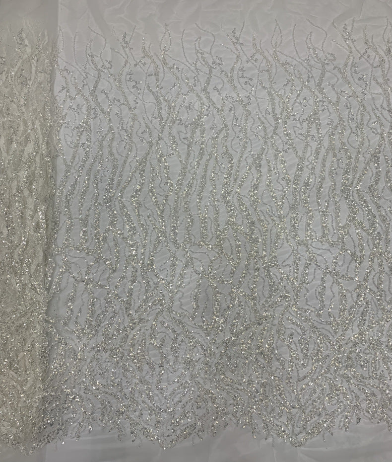 Close-up of silver beaded floral scroll pattern on ivory transparent fabric