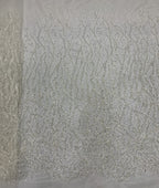 Close-up of silver beaded floral scroll pattern on ivory transparent fabric