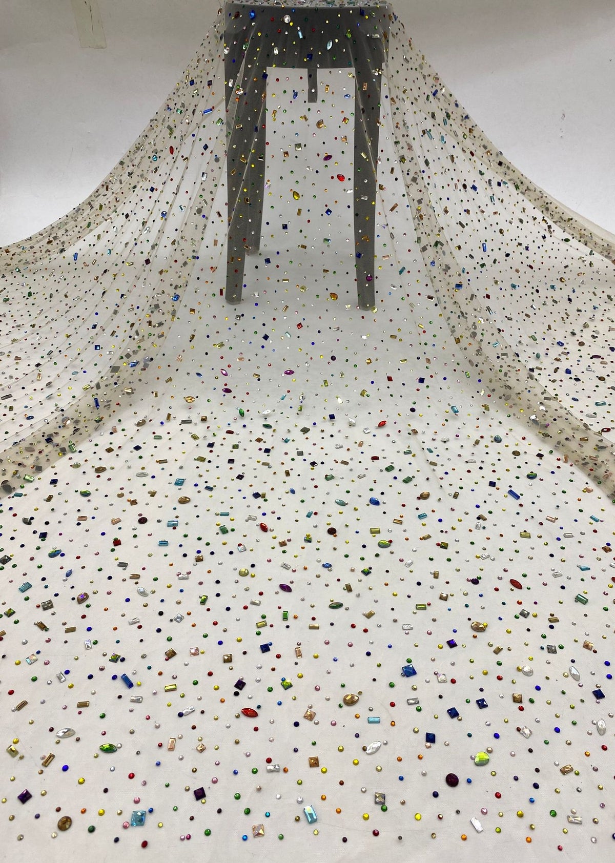 Ivory sheer gown fabric scattered with metallic rhinestones shown as a full drape