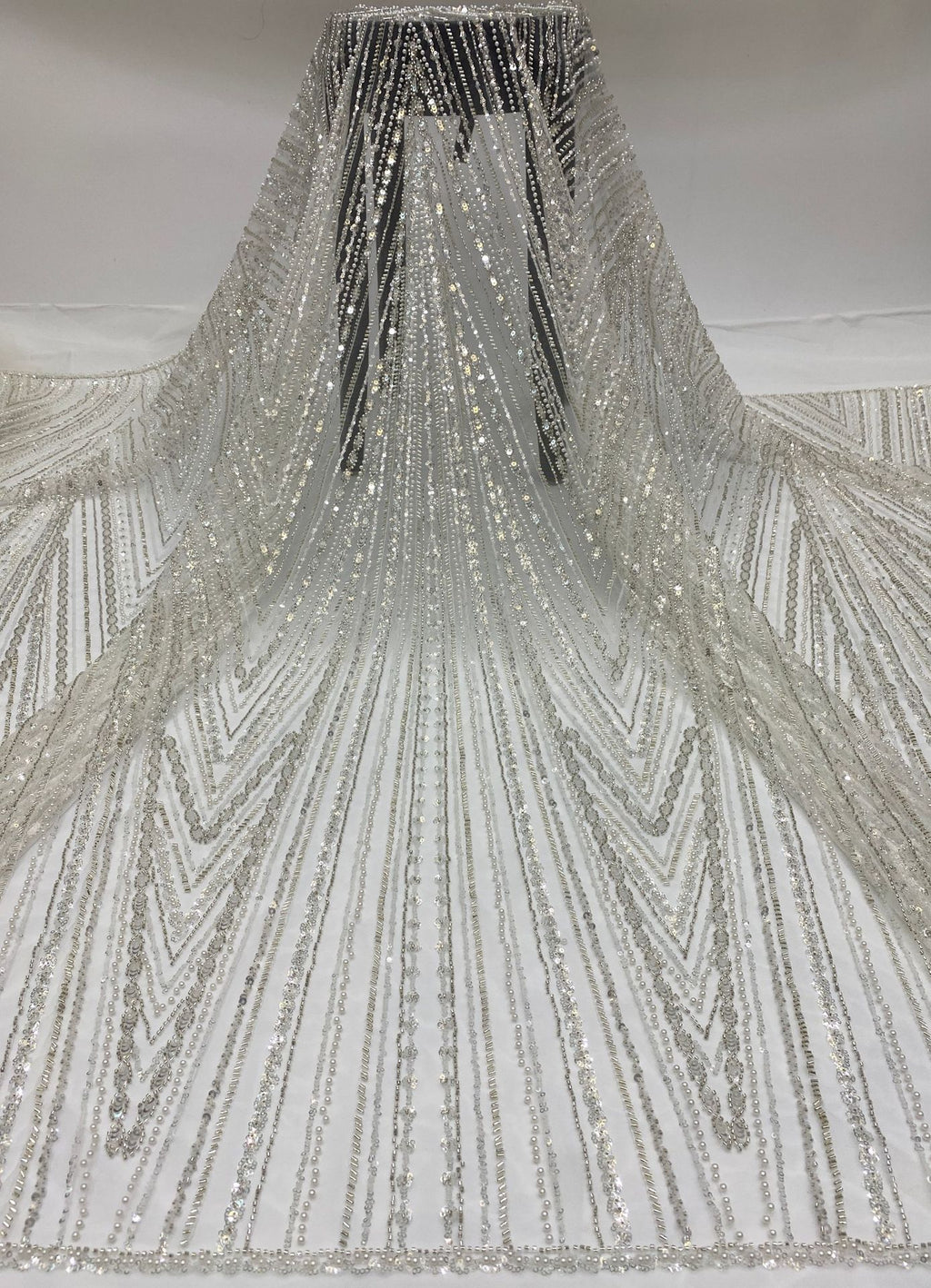 Ivory sheer bridal fabric draped to show long radiating silver bead and sequin lines