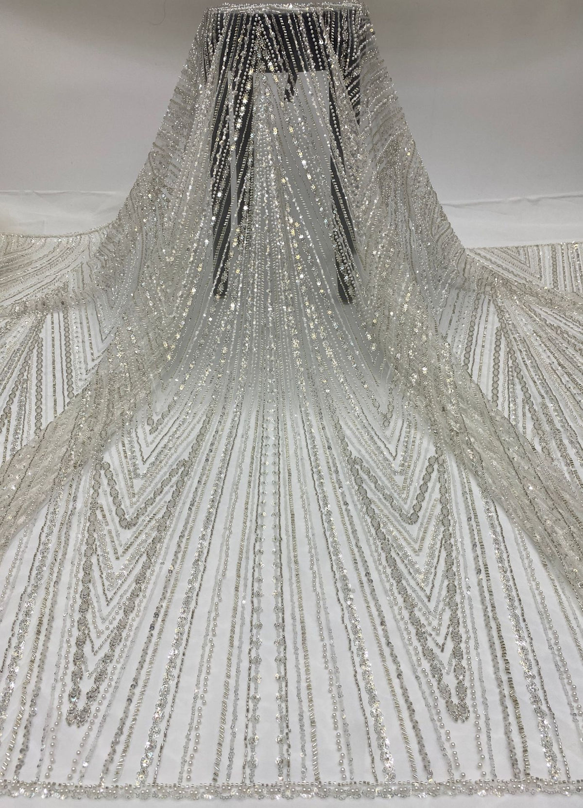 Ivory sheer bridal fabric draped to show long radiating silver bead and sequin lines