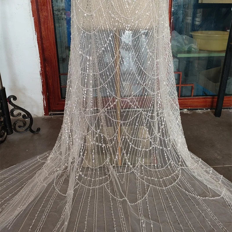فستان زفاف رائع من اللؤلؤ الأبيض من قماش الدانتيل المجوف من اللؤلؤ المطرز بالخرز والأظافر وتصميم الملابس وإكسسوارات الدانتيل