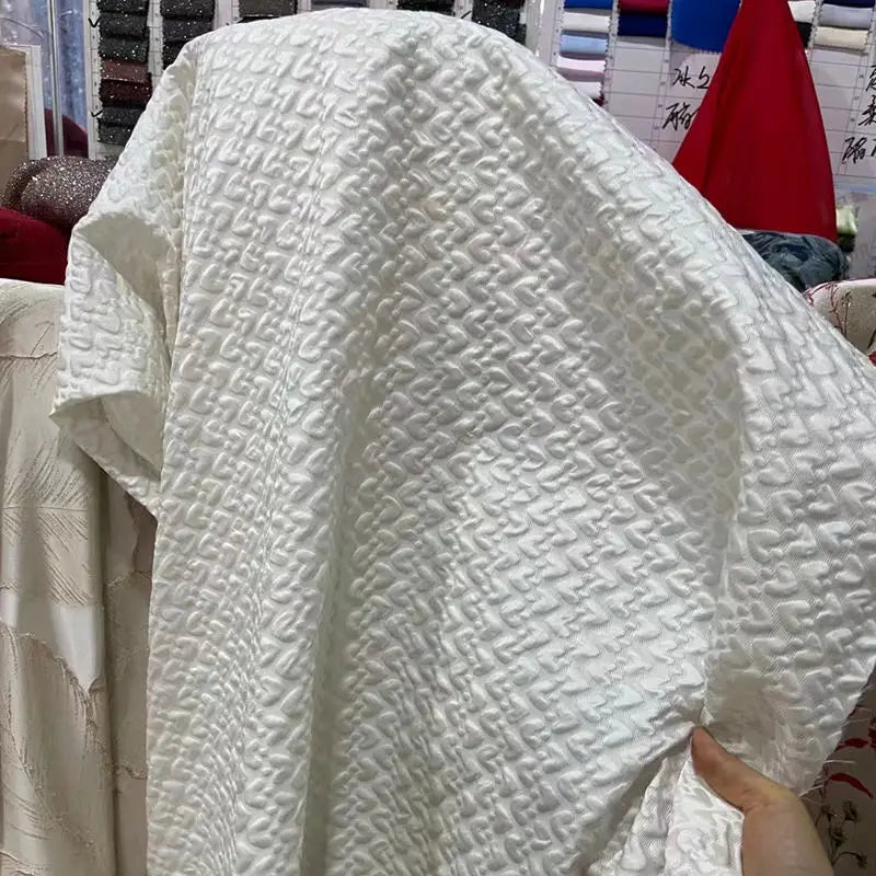 Esta tela satinada con relieve jacquard blanco es una tela tridimensional creativa de cuadros retro para chaquetas, faldas, bolsos y diseños.