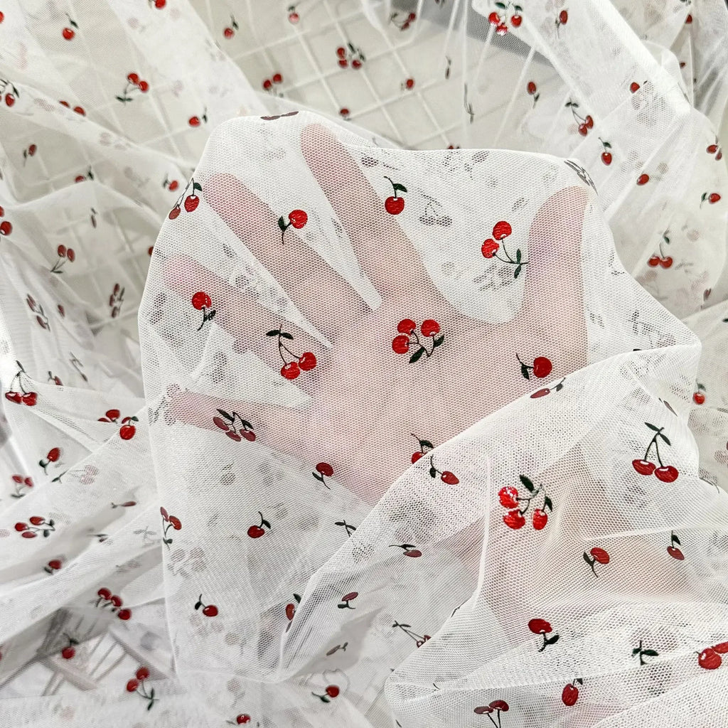 Tejido de malla elástica suave con hilo dorado y estampado de cerezas - Material transparente