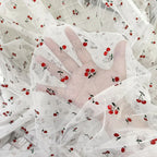 Tejido de malla elástica suave con hilo dorado y estampado de cerezas - Material transparente