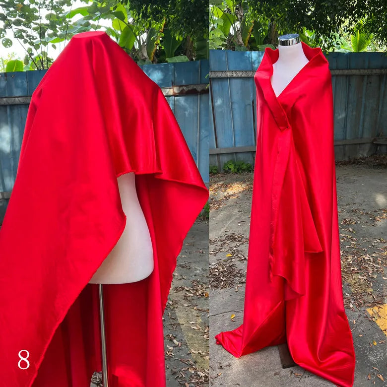 Bright red glossy satin fabric draped on a dress form and shown hanging outdoors