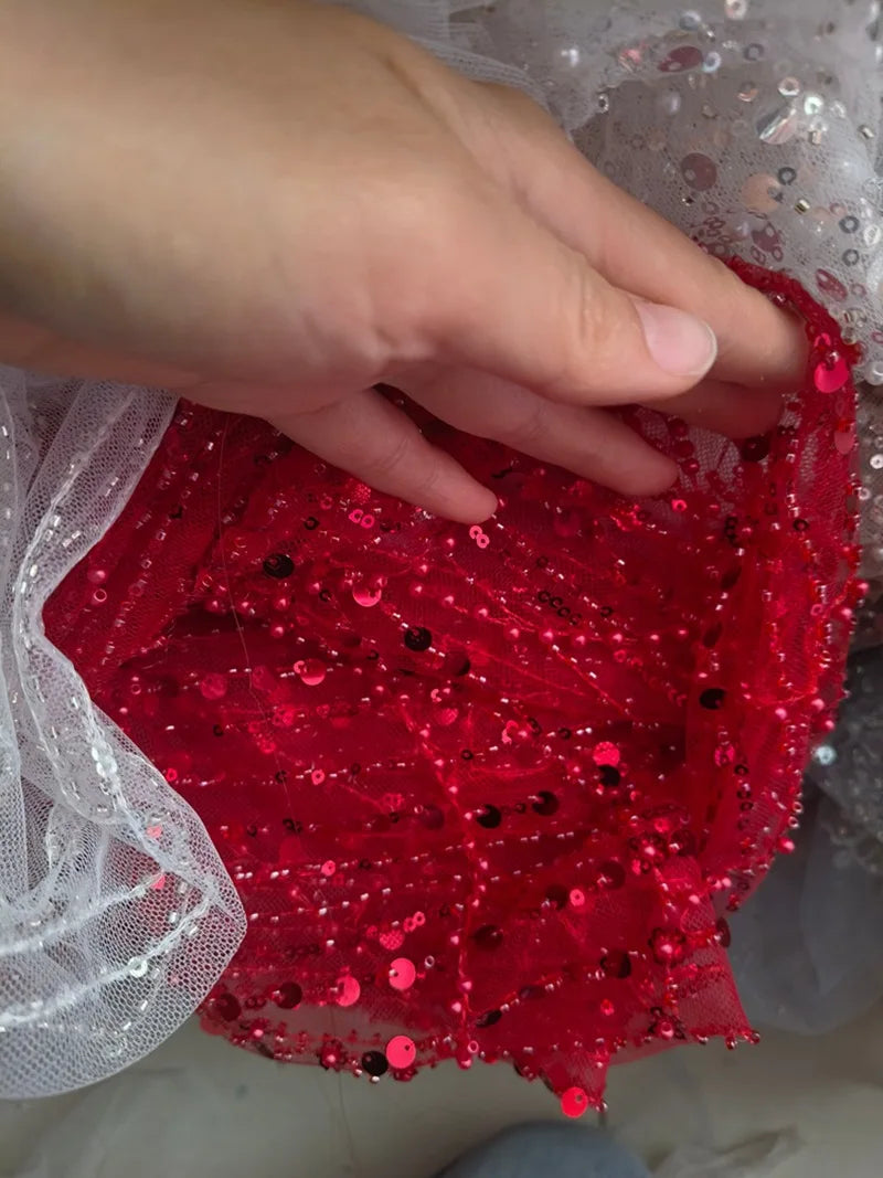 فستان زفاف رائع من اللؤلؤ الأبيض من قماش الدانتيل المجوف من اللؤلؤ المطرز بالخرز والأظافر وتصميم الملابس وإكسسوارات الدانتيل