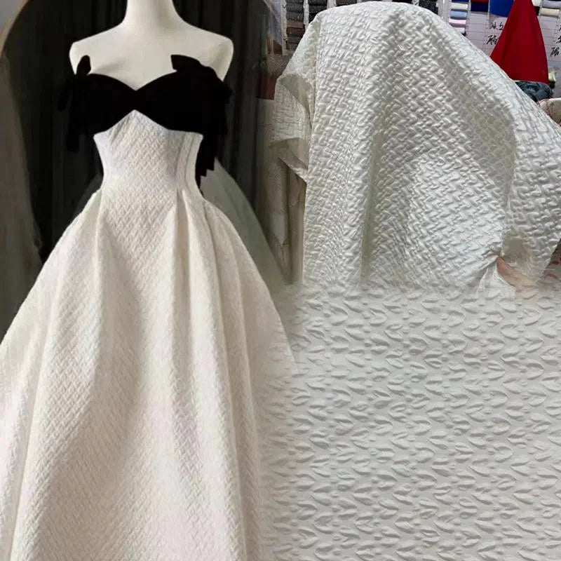 Esta tela satinada con relieve jacquard blanco es una tela tridimensional creativa de cuadros retro para chaquetas, faldas, bolsos y diseños.